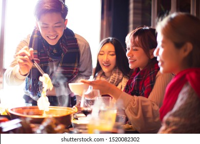 happy young friends eating hot pot in restaurant at winter