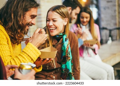 Happy young friends eating takeaway food outdoor - Focus on left man face - Powered by Shutterstock