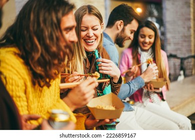 Happy young friends eating takeaway food outdoor - Focus on left girl face - Powered by Shutterstock