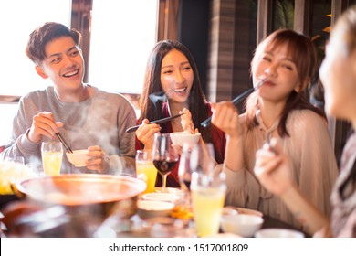 happy young friends enjoy dinner in hot pot restaurant 