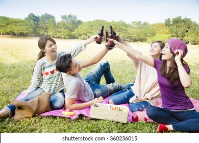 Happy Young Friends Enjoying Picnic And Drinking Beer