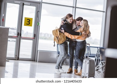 Happy Young Friends Hugging In Airport Terminal