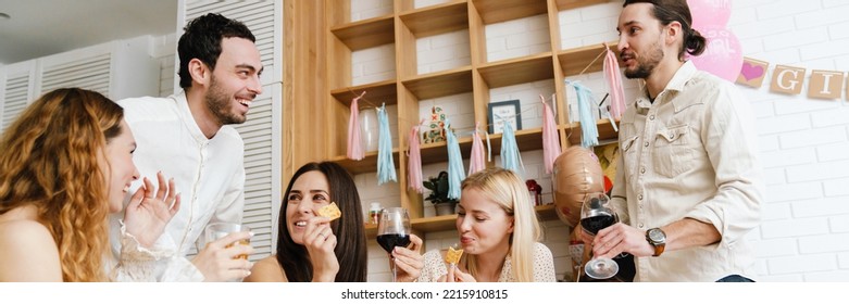 Happy Young Friends Laughing And Eating Snacks During Gender Reveal Party Indoors