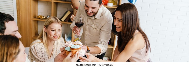 Happy Young Friends Laughing And Eating Muffins During Gender Reveal Party Indoors