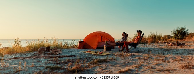 Happy young friends resting by the bonfire near tent. - Powered by Shutterstock