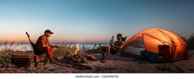 Happy young friends resting by the bonfire near tent. - Powered by Shutterstock