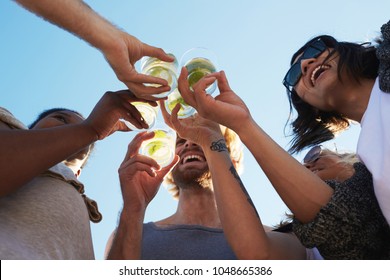 Happy young friends toasting with refreshing drinks under blue sky on summer day - Powered by Shutterstock