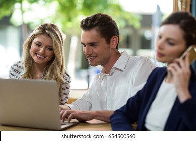 Happy young friends using laptop in cafÃ© - Powered by Shutterstock