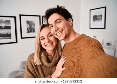 Happy Young Gen Z Couple Hugging Having Fun Looking At Camera, Holding Phone Taking Selfie, Shooting Vlog Or Having Virtual Chat Video Call At Home, Close Up Headshot Portrait, Camera View.