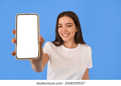 Happy young gen z Latin girl shopper girl student holding smartphone using mobile cell phone showing big mockup screen advertising new sale app promo on cellphone app isolated on blue background.