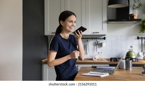 Happy Young Gen Z Student Girl Using Virtual Voice Assistant For Internet Search, Giving Vocal Command To Online App, Talking, Chatting On Mobile Phone On Speaker. Communication Concept