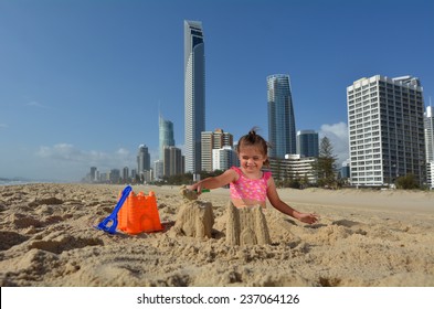 Happy young girl (age 04) building sand castle on Surfers Paradise main beach in Gold Coast Queensland, Australia. Real people. Copy space