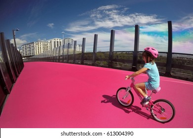 Happy young girl (age 07) ride a bike on  bright pink cycleway in Auckland, New Zealand. Real people. Copy space