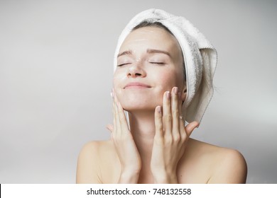 happy young girl with clean skin and with a white towel on her head washes face - Powered by Shutterstock