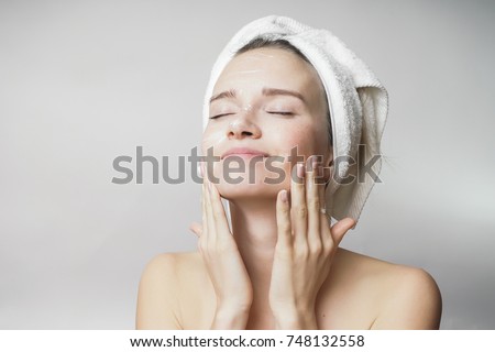 happy young girl with clean skin and with a white towel on her head washes face