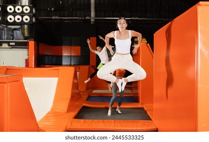 Happy young girl doing jumping at the trampoline center - Powered by Shutterstock