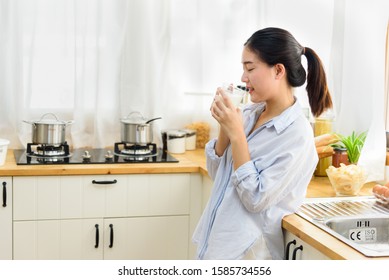 Happy young girl drink a milk for breakfast in kitchen conner. Healthy eating and lifestyle concept.