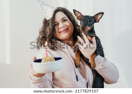 Happy young girl giving homemade cake to her dog, indoors. Concept of childfree by choice and celebrating dog's birthday party