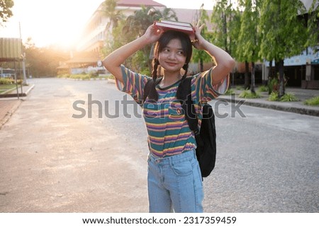 Happy young girl hold book with backpack walking at school.