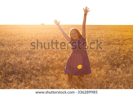 happy young girl joys at the wheat field at the evening time
