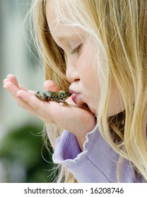 Happy Young Girl Kissing A Frog