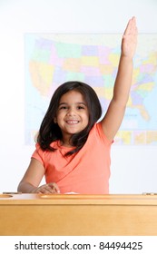 Happy Young Girl Raising Hand In School