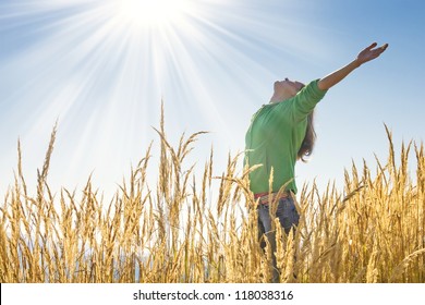 Muchacha feliz levantando sus brazos con alegría y alegría en la alta hierba en un hermoso día soleado