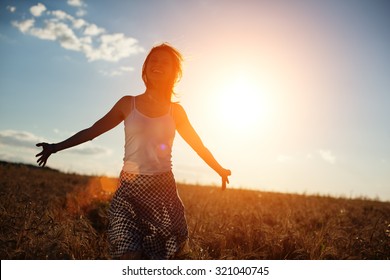 Happy Young Girl Running In The Field At Sunset (intentional Sun Glare And Lens Flares)