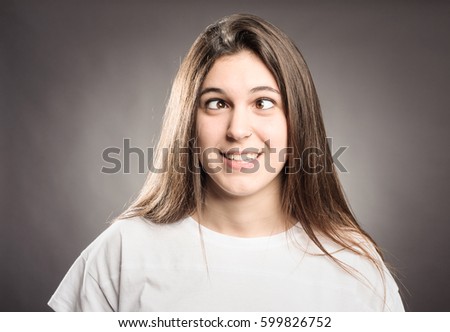 happy young girl squinting on a gray background