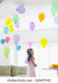 Happy Young Girl Standing In Room Full Of Balloons