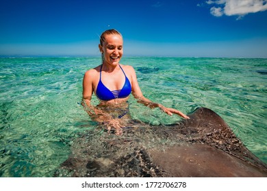 Happy Young Girl Swimming With Two Stingray In Ocean