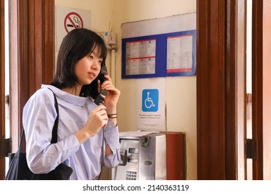 Happy Young Girl Talking On Traditional Red Fixed Land Line Pay Telephone