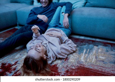 Happy young girl, teenager lying on the floor at home and smoking marijuana joint. She is smiling and relaxing with her boyfriend. Weed legalization. Ganja, cannabis, friends using light drugs