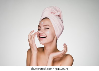 happy young girl with a towel on her head apply a cleansing mask on her face