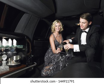 Happy young glamorous couple enjoying champagne in limousine
