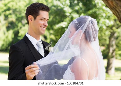 Happy young groom unveiling his bride in garden - Powered by Shutterstock