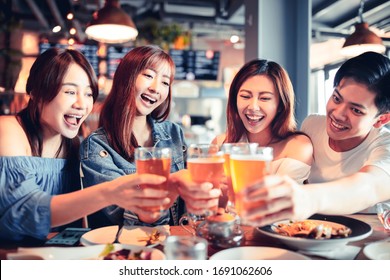 Happy Young Group Dining And Drinking Beer At Restaurant