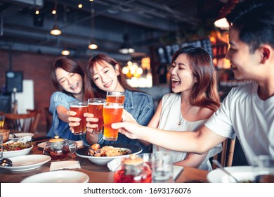 Happy Young Group Dining And Drinking Beer At Restaurant