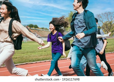 Happy young group students running Across Field
