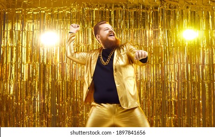 Happy Young Guy Celebrating Success And Enjoying Disco Party. Excited Chubby Man In Funny Shiny Golden Suit Having Fun, Dancing Like Crazy And Doing Rope Move Like Cowboy With Lasso