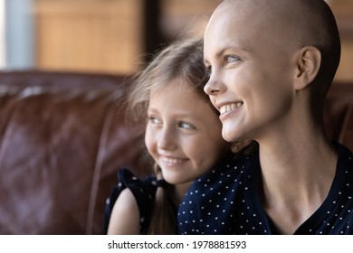 Happy Young Hairless Woman Fighting Against Cancer, Spending Time With Little Daughter, Looking Away, Thinking Of Good Future. Kid Hugging Optimistic Mom With Gratitude, Enjoying Leisure Together