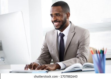 Happy young handsome african american businessman working alone in the office - Powered by Shutterstock