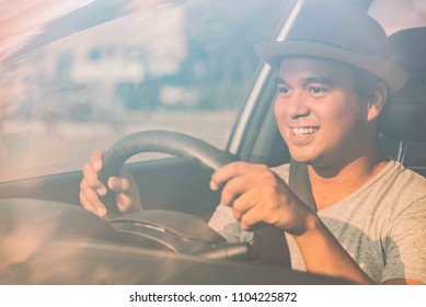 Happy Young Handsome Asian Man With Hat Driving Car On The Road To Travel On Holiday.Man In Safety Vehicle And Car Insurance Concept.