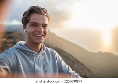 Happy young handsome guy, making selfie portrait on a mountain hill in sunset light. - Powered by Shutterstock