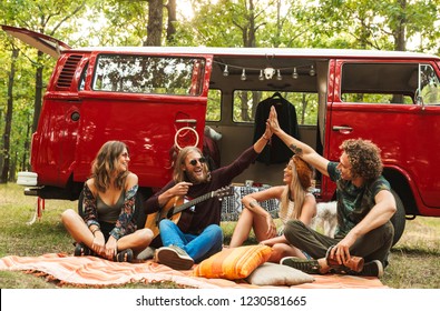 Happy young hipsters men and women laughing and playing guitar near vintage minivan into the nature - Powered by Shutterstock