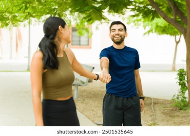 Happy young hispanic couple in athletic attire holding hands and smiling during a leisurely break from their outdoor workout - Powered by Shutterstock