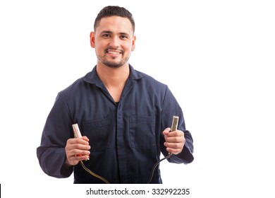 Happy young Hispanic man holding a couple of jumper cable terminals on a white background - Shutterstock ID 332992235