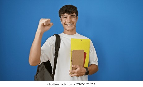 Happy young hispanic teenager student with backpack celebrating while holding books, standing isolated on a blue background in a cool, confident and smart lifestyle portrait. - Powered by Shutterstock