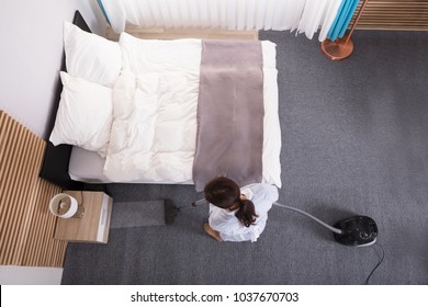 Happy Young Housekeeper Cleaning Carpet With Vacuum Cleaner In Hotel Room