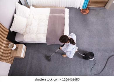 Happy Young Housekeeper Cleaning Carpet With Vacuum Cleaner In Hotel Room